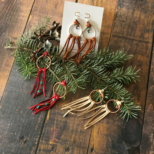 three pairs of leather fringe earrings by Buckaroo Bling on an evergreen branch