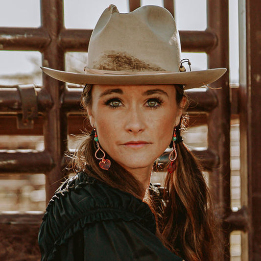 Model in a light cowboy hat wearing Buckaroo Bling turquoise earrings with real aspen leaves dipped in copper