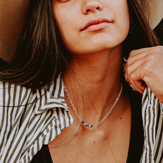 Dainty turquoise and sterling silver necklace on a model wearing a striped shirt