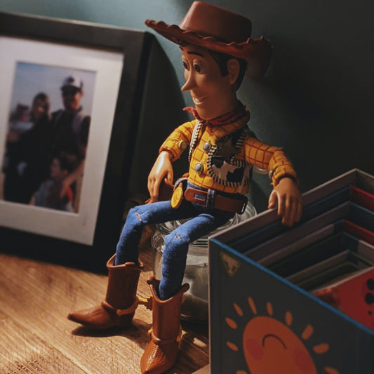 Cowboy doll sitting on a shelf next to a box and a family picture; photo by David Briggs